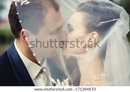European bride and groom kissing in the park. Wedding shot of elegant bride and groom posing together outdoors on a wedding day. wedding dress. Bridal wedding bouquet of flowers.