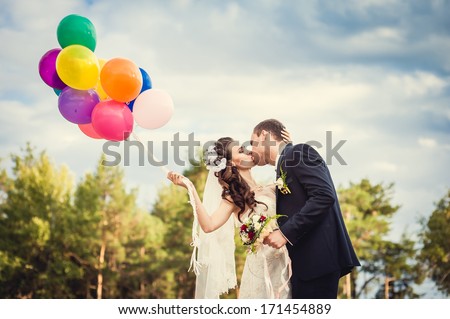 Beautiful Bride Holding Bunch Of Red Balloons On Park. Couple Of Bride And Groom With Balloons. Newlyweds With Balloons Outdoors. Happy Valentines Day!