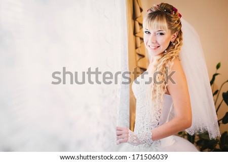 Gorgeous smiling blonde bride in front of a window. Happy Bride looking in window