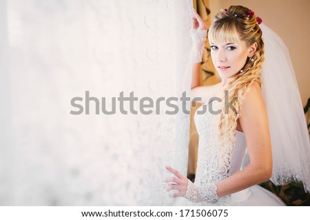 Gorgeous smiling blonde bride in front of a window. Happy Bride looking in window