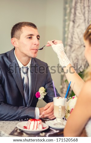 Cute married couple in cafe, groom kissing a bride. Pure tenderness. Bride and groom drinking coffee at an outdoor cafe. a romantic rest in vintage cafe interior.