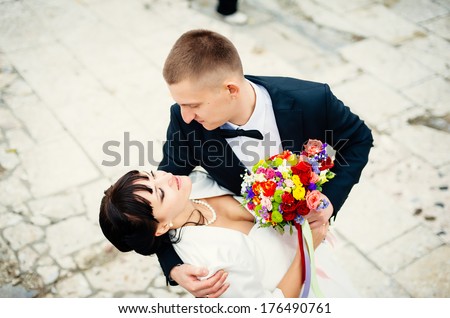 Groom and Bride in a park. Young couple kissing in wedding gown. wedding dress. Bridal wedding bouquet of flowers
