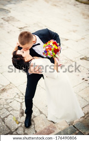 Groom and Bride in a park. Young couple kissing in wedding gown. wedding dress. Bridal wedding bouquet of flowers