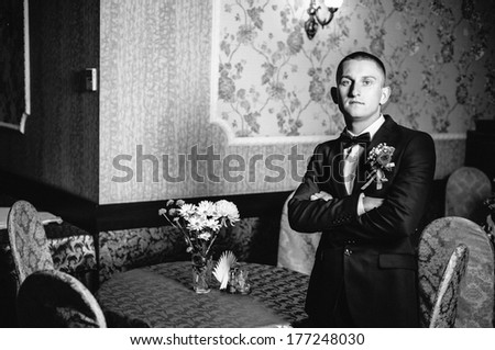 Handsome groom at wedding tuxedo smiling and waiting for bride  in a luxurious restaurant. Happy smiling groom newlywed. Rich groom at wedding day. Handsome caucasian man in tuxedo.