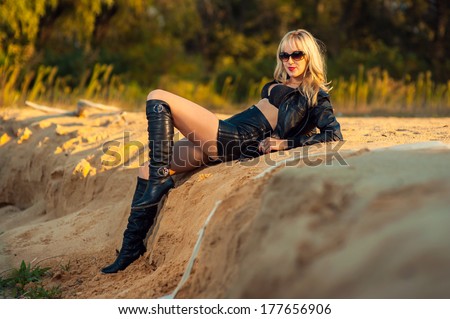 beautiful girl in jeans and a leather jacket in the desert. Sexy Girl in leather dress on the sand. Gorgeous beautiful sexy woman in lingerie and black leather jacket