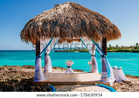 Beautiful Decorated Romantic Wedding Table on Sandy Tropical Caribbean Dominican Beach at Sunset. Wedding arch decorated on caribbean beach. gazebo for wedding ceremony on the coast