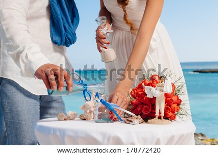 sand ceremony being performed at wedding. Hands of bride holding vase with colorful sand during wedding party