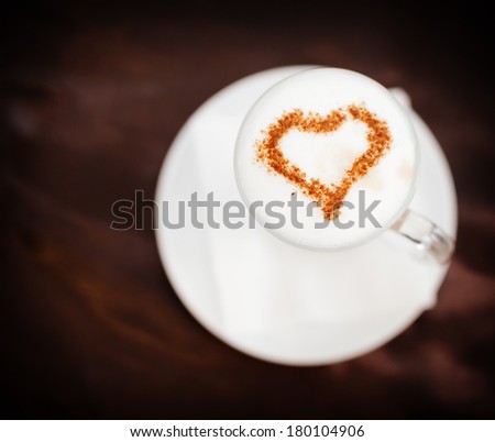 Cappuccino or latte coffee with heart shape. A cup of coffee with heart pattern in a white cup on wooden background