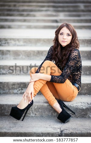 beautiful young woman smiling. young woman in colorfull summer clothes sit on stairs outdoor shot