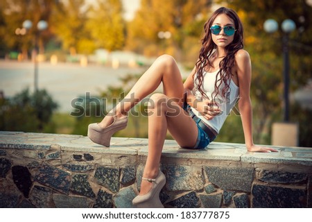 beautiful young woman smiling. young woman in colorfull summer clothes sit on stairs outdoor shot