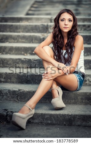 Portrait of a beautiful young woman sitting on stairs outdoors. beautiful young woman smiling. young woman in colorfull summer clothes sit on stairs outdoor shot