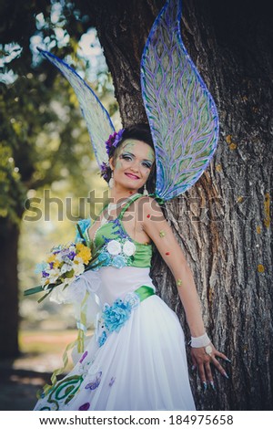 Beautiful girl in suit of fairy. Magical young woman as fairy with wings. Beautiful young brunette woman as summer fairy