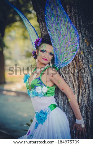 Beautiful girl in suit of fairy. Magical young woman as fairy with wings. Beautiful young brunette woman as summer fairy