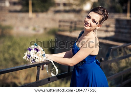 Beautiful woman in blue dress with bouquet of flowers posing outdoor. bride in blue dress with bouquet of flowers