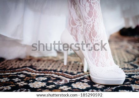 Bridal Shoes. beautiful bride in white wedding dress. Happy sexy girl waiting for groom. Romantic lady in bridal dress and flowers in hair have final preparation for wedding