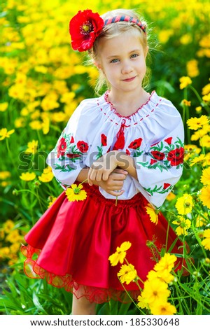 Ukrainian girl dress standing in a field of yellow flowers. Beautiful girl in ukrainian costume standing outdoor. little girl with flowers.  Mothers day concept
