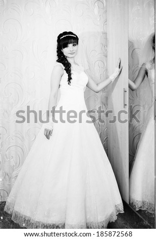 beautiful bride in white wedding dress with hairstyle and bright makeup. Happy sexy girl waiting for groom. Romantic lady in bridal dress and flowers in hair have final preparation for wedding