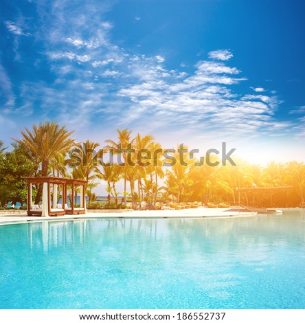 Beautiful sunset at a beach resort in the tropics. Pool at tropical beach - vacation background.