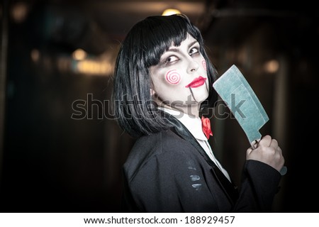 Scary portrait of an angry woman with a sharp knife bathed in the blood. one strange young woman killer holding bloody knife. Halloween. Criminal woman in vintage black coat with an ax in his hands