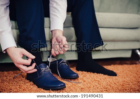groom putting his wedding shoes. Hands of wedding groom getting ready in suit