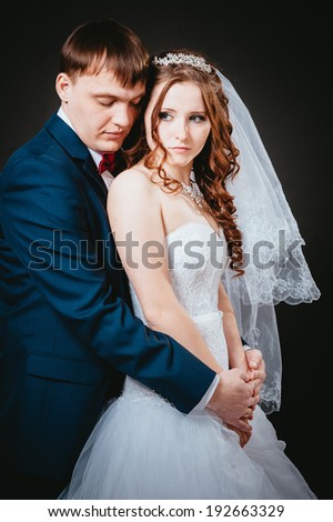 Loving bride and groom in studio. newly-married couple on the isolated black background. Affectionate bride and groom with head to head.