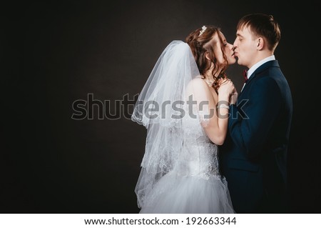 Loving bride and groom in studio. newly-married couple on the isolated black background. Affectionate bride and groom with head to head.