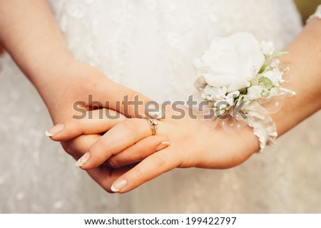 Bride\'s hands with ring over her wedding dress