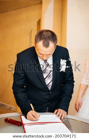 wedding official ceremony in registry office, ukraine.  A newly-married couple signs the marriage document.Young couple signing wedding documents.