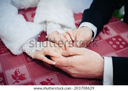 Bride and groom posing at the decorated banquet table in the park in the summer. Hand in hands. Enjoy a moment of happiness and love. A series of photos in my portfolio. Wedding flowers on a table