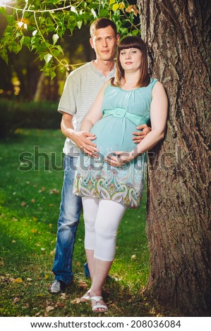 Belly of a pregnant woman with her husband on the nature. A young man hugging his pregnant happy wife,outdoor. Beautiful belly of young attractive pregnant woman with her husband walking outdoor