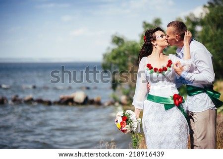 Ukraine. Happy Ukrainian wedding bridal couple in the ukrainian style. Beautiful bride and groom in the ukrainian style are standing with bouquet. Female and male models. Outdoor. park summer outdoor