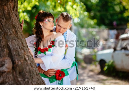 Ukraine. Happy ukrainian wedding (bridal) couple in the ukrainian style. Beautiful bride and groom in the ukrainian style are standing with bouquet. Female and male models. park summer outdoor