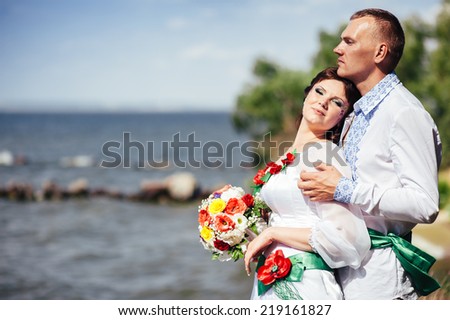 Ukraine. Happy ukrainian wedding (bridal) couple in the ukrainian style. Beautiful bride and groom in the ukrainian style are standing with bouquet. Female and male models. park summer outdoor