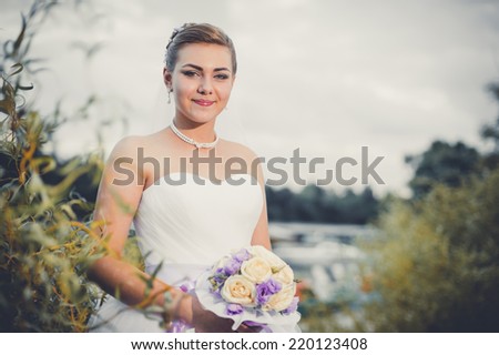 Bride walking along sea coast wearing beautiful wedding dress. portrait of a smiling woman bride in a beautiful white wedding dress with bouquet of flowers on the beach near the sea