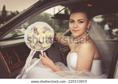 Portrait of a pretty bride in a car. closeup portrait of a pretty shy bride in a car window. bride in the car. wedding bouquet. cheerful face