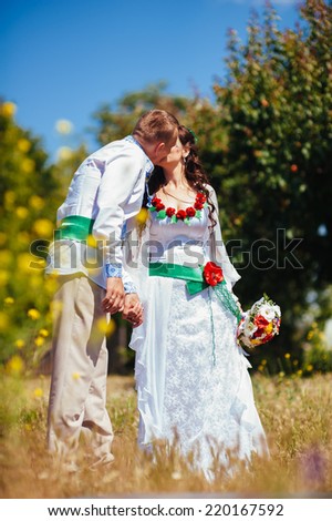 Ukraine. Happy ukrainian wedding (bridal) couple in the ukrainian style. Beautiful bride and groom in the ukrainian style are standing with bouquet. Female and male models. . park summer outdoor