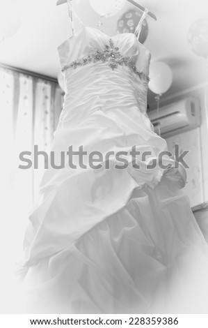 Wedding dress hanging on a shoulder. wedding dress hanging up by the window