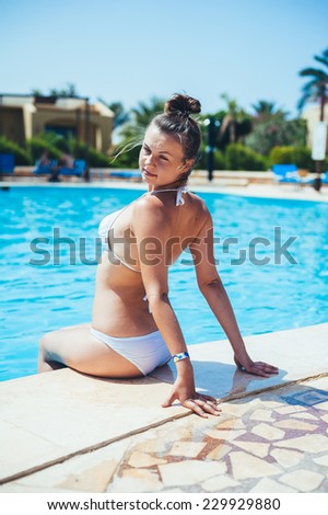 Sexy blonde woman in bikini posing in swimming pool. beautiful long hair female model posing by the pool, outdoor portrait