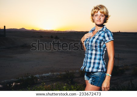 Sexy beautiful young woman at sunset in desert. Young woman walking outside in late evening desert sunshine. Ethereal image evoking dreamy freestyle fashion youth emotion