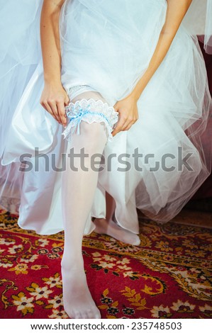 female bride leg in sexy white silk stocking. Young bride is putting on white stocking.