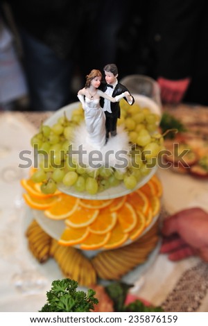 fruit sliced grapes and orange. wedding table. figurines of the bride and groom. Plate full of sliced fresh grapefruits, oranges on a festive table