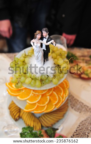 fruit sliced grapes and orange. wedding table. figurines of the bride and groom. Plate full of sliced fresh grapefruits, oranges on a festive table