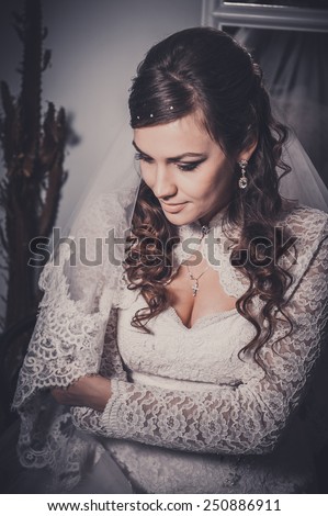 Gorgeous bride blonde in wedding dress in luxury interior with diamond jewelry posing at home and waiting for groom. Romantic rich brunette bride in a luxurious wedding dress in  expensive interior