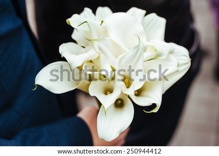 Groom handing wedding bouquet to bride. Wedding bouquet in groom's hands