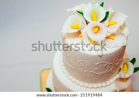wedding cake decorated with flowers. Wedding cake with white icing and bow. Wedding luxurious  restaurant decoration. Table setting at a luxury wedding reception.