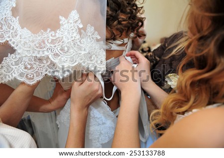 Bridesmaid is helping the bride to dress. bridesmaid tying bow on wedding dress.