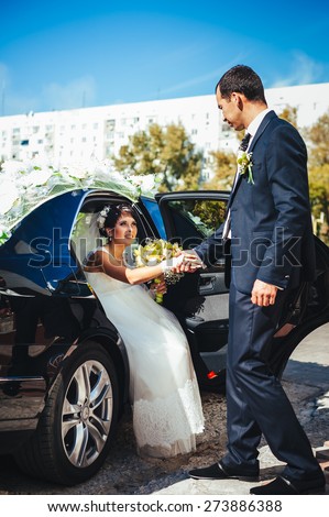 Happy groom helping his bride out of the wedding car. newly wedded standing near wedding car.