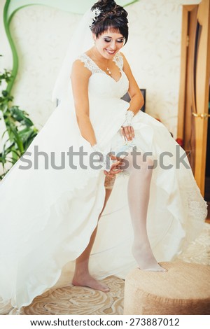 Bride putting a wedding garter on her leg.