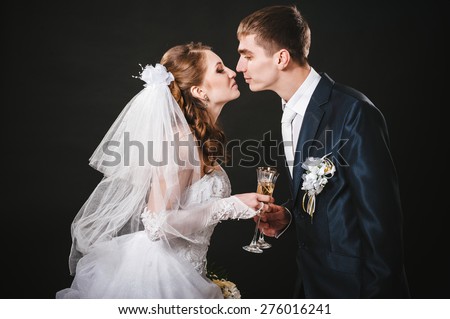 Wedding couple kissing and drinking champagne. Black background. bride groom bouquet drinking champagne wedding dress black studio background