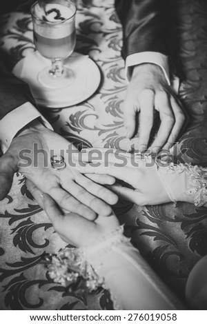Couple\'s hands on the table and wedding rings and bridal bouquet flowers